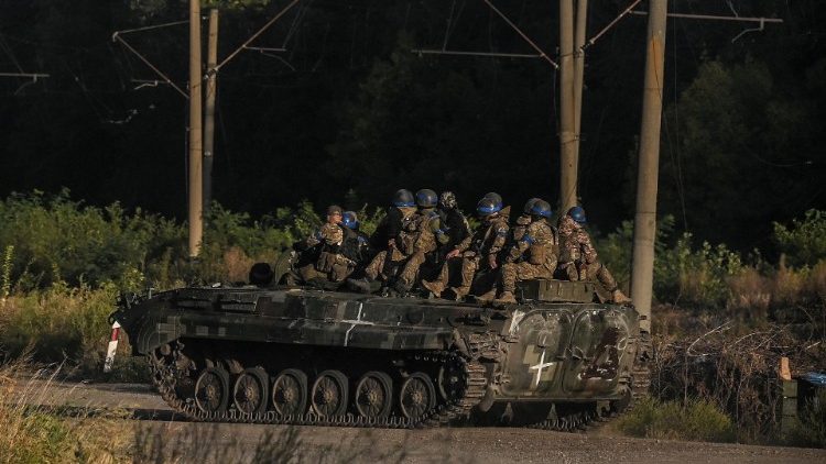 Ukrainian troops sit atop an armed vehicle in Kharkiv