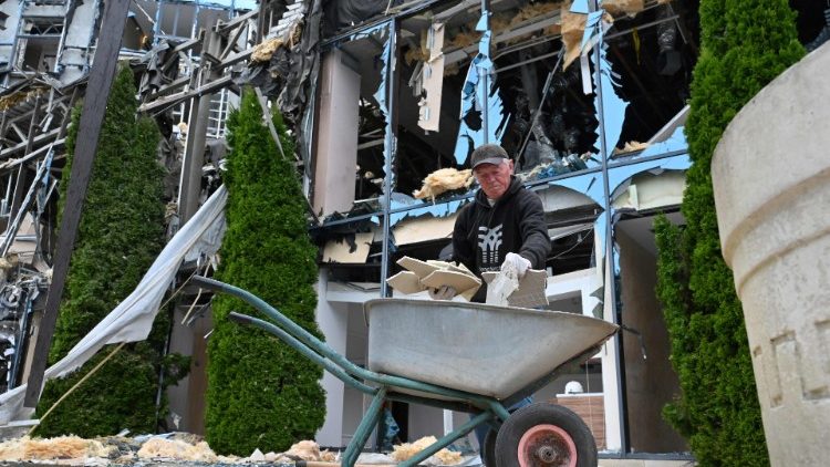 Um trabalhador comunitário limpa os destroços do lado de fora do centro de entretenimento Misto (Cidade) parcialmente destruído como resultado de um ataque com mísseis, em Kharkiv, em 11 de setembro de 2022, em meio à invasão russa da Ucrânia. (Foto de SERGEY BOBOK/AFP)