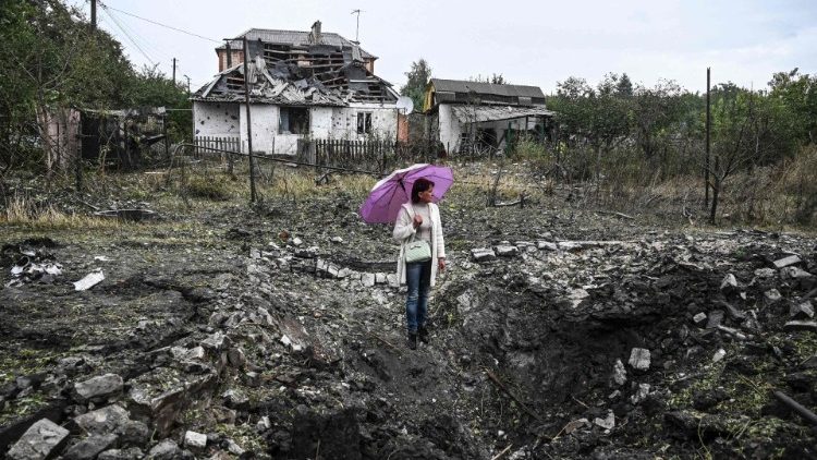 Uma mulher em frente a uma casa destruída, em Kramatorsk, região de Donetsk, em 12 de setembro de 2022, em meio à invasão russa da Ucrânia. (Foto de Juan BARRETO/AFP)