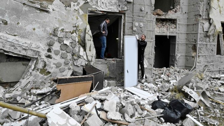 Moradores locais ficam do lado de fora de seu prédio parcialmente destruído por um ataque com mísseis em Kharkiv em 12 de setembro de 2022 em meio à invasão russa da Ucrânia. (Foto de SERGEY BOBOK/AFP)