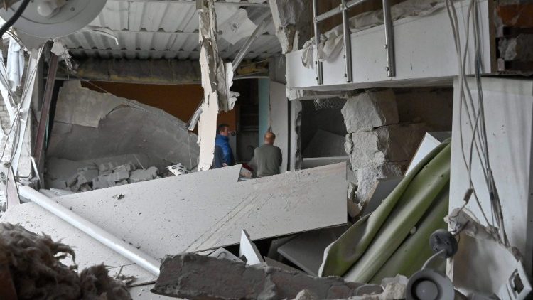 Moradores locais ficam dentro de seu prédio parcialmente destruído por um ataque de míssil em Kharkiv em 12 de setembro de 2022 em meio à invasão russa da Ucrânia. (Foto de SERGEY BOBOK/AFP)