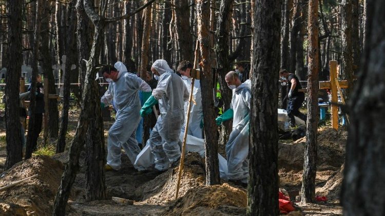Conteúdo gráfico / Técnicos forenses carregam um saco de cadáveres no local de uma vala comum em uma floresta nos arredores de Izyum, leste da Ucrânia, em 18 de setembro de 2022. dos corpos exumados com sinais de tortura. (Foto de Juan BARRETO/AFP)