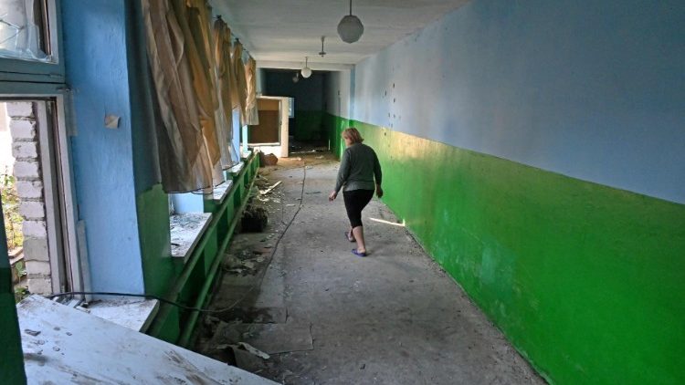 Um funcionário caminha no corredor da escola que foi usada pelas tropas como base na vila de Nova Husarivka, não muito longe de Balakliya, região de Kharkiv, em 18 de setembro de 2022, recentemente recapturada pelo exército ucraniano após a retirada das tropas russas. (Foto por SERGEY BOBOK/AFP)