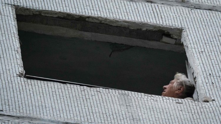 Uma mulher olha para cima de uma janela destruída em um prédio residencial atingido por um ataque com mísseis em Kharkiv em 21 de setembro de 2022, em meio à invasão russa da Ucrânia. (Foto de Yasuyoshi CHIBA/AFP)