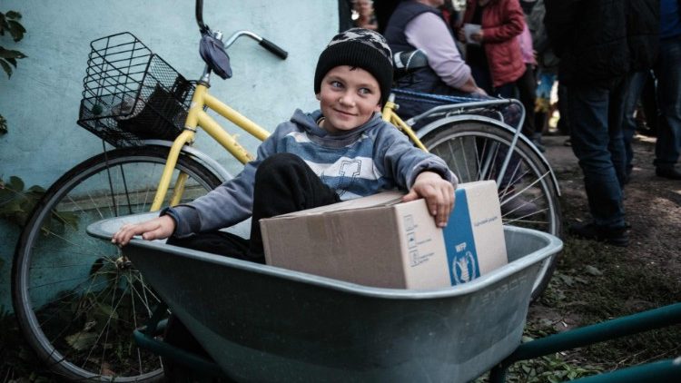 9-letni Denis otrzymujący podstawowe produkty żywnościowe w wiosce Łebjaże, Ukraina