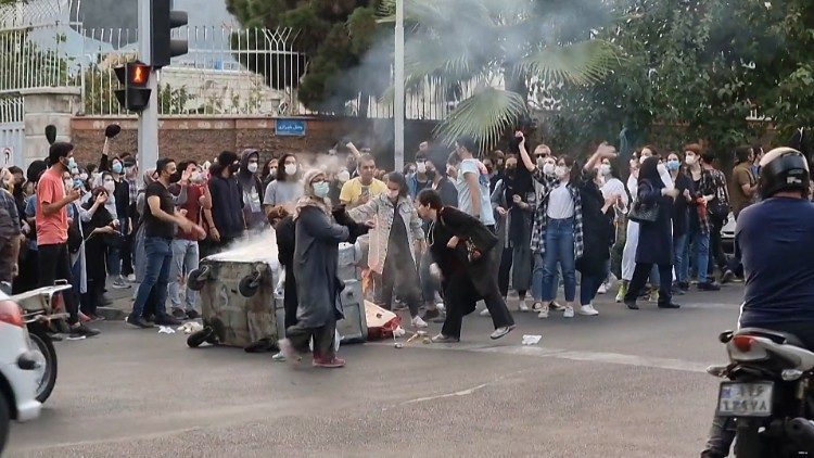 Iranian demonstrators burning their headscarves and setting fire to a trash bin in the capital Tehran