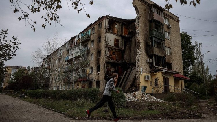 Um homem corre em frente a um prédio de apartamentos destruído em Bakhmut, região de Donetsk, em 26 de setembro de 2022, em meio à invasão russa da Ucrânia. (Foto de ANATOLII STEPANOV/AFP)