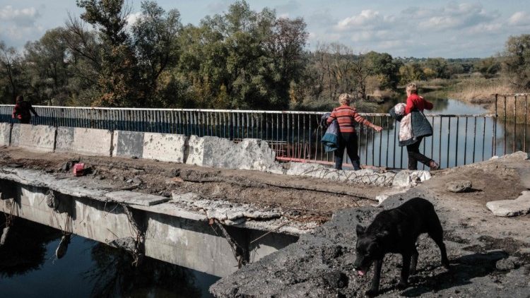 Pedestres caminham em uma ponte destruída sobre o rio Oskil enquanto evacuam da margem leste recentemente retomada em Kupiansk, região de Kharkiv, em 29 de setembro de 2022. (Foto de Yasuyoshi CHIBA / AFP)