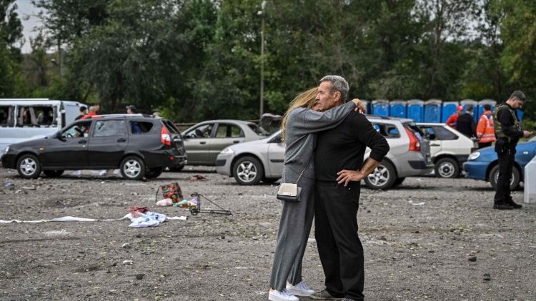 Um casal se abraça perto de carros danificados por um ataque de míssil em uma estrada perto de Zaporizhzhia em 30 de setembro de 2022, em meio à invasão russa da Ucrânia. - Ucrânia em 30 de setembro, culpou Moscou por bombardear um comboio de carros civis na região sul de Zaporizhzhia que matou pelo menos 25 perto da linha de frente. (Foto de Genya SAVILOV / AFP)