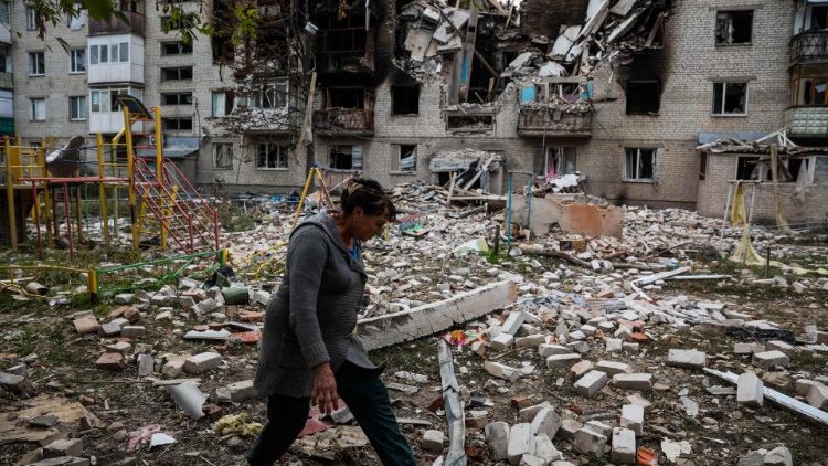 Um pedestre caminha em um pátio de um prédio destruído na cidade de Sviatohirsk, região de Donetsk, em 30 de setembro de 2022, em meio à invasão russa da Ucrânia. , (Foto de ANATOLII STEPANOV/AFP)