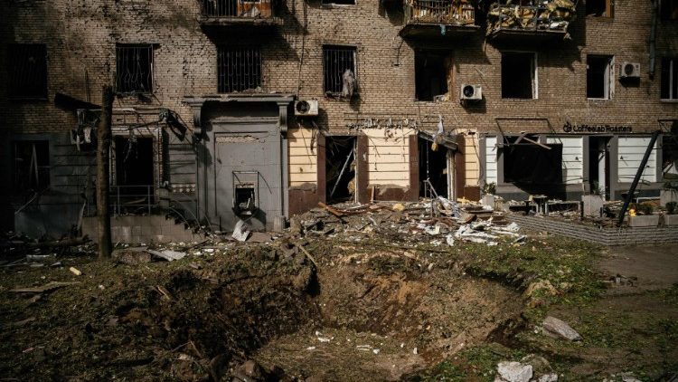 Uma fotografia tirada em 6 de outubro de 2022 mostra uma cratera e um prédio de apartamentos danificado após um ataque em Zaporizhzhia em 6 de outubro de 2022, em meio à invasão russa da Ucrânia. (Foto de Dimitar DILKOFF/AFP)
