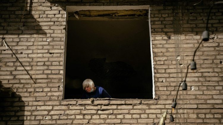 Uma mulher olha pela janela de um prédio de apartamentos danificado após um ataque em Zaporizhzhya em 6 de outubro de 2022, em meio à invasão russa da Ucrânia. (Foto de Dimitar DILKOFF/AFP)