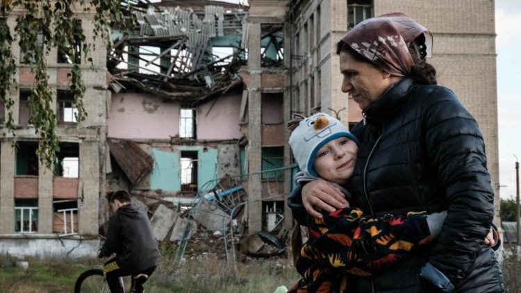 Olga Srednyakova (R), 51, mãe solteira dos oito filhos, abraça a filha mais nova Vera, 8, enquanto outros colhem cogumelos em um terreno abandonado de sua escola destruída em Konstantinovka, na região de Donetsk, em 13 de outubro de 2022, em meio a a invasão russa da Ucrânia. (Foto de Yasuyoshi CHIBA/AFP)