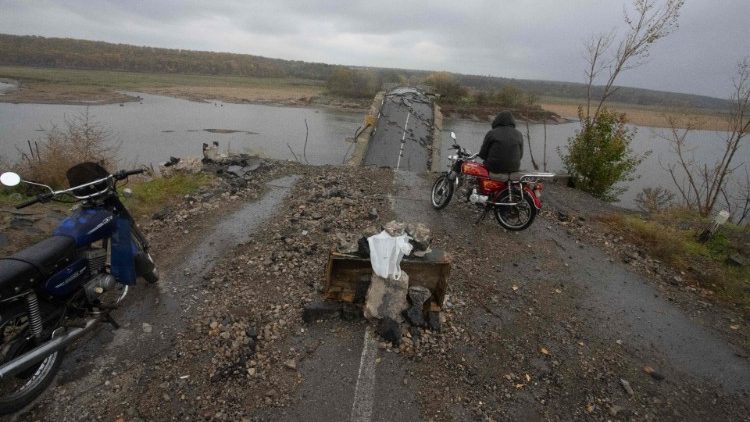 Um morador local observa uma ponte destruída perto de Borivske, região de Kharkiv, em 23 de outubro de 2022. (Foto de Yevhen TITOV / AFP)