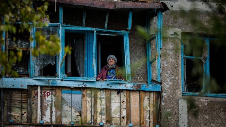 Uma idosa fica na varanda de sua casa danificada após um bombardeio na cidade de Bakhmut, na região de Donetsk, em 25 de outubro de 2022, em meio à invasão russa da Ucrânia. - Após a morte de sete civis em 24 de outubro, em Bakhmut, os moradores remanescentes da pequena cidade mineira no leste da Ucrânia, devastada pelo fogo cruzado nos últimos três meses, estão se agarrando à decisão de ficar, arriscando suas vidas. (Foto de Dimitar DILKOFF/AFP)