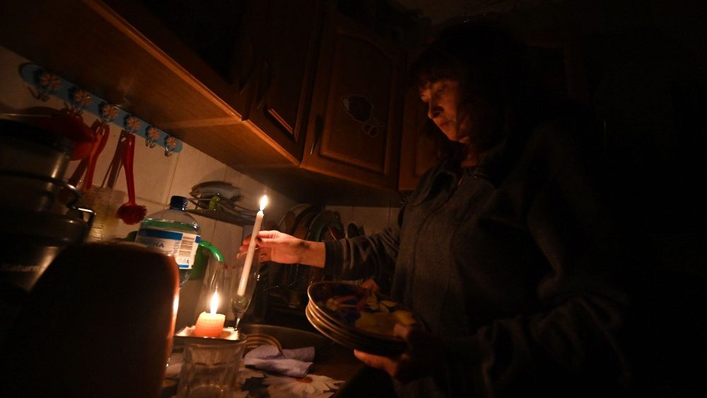 Esta fotografia tirada em 5 de novembro de 2022 mostra Iren Rozdobudko, um escritor e professor universitrio de 60 anos, limpando pratos  luz de velas durante um corte de energia no prdio no norte da capital ucraniana de Kyiv. - Desde 10 de outubro, o sistema eltrico ucraniano foi fortemente afetado por vrios ataques russos que atingiram a infraestrutura de energia. Para evitar um apag?o total, a operadora nacional Ukrenergo implementou cortes de energia programados na capital, bem como em muitas cidades e regi?es da Ucr?nia. (Foto de Sergei SUPINSKY/AFP)