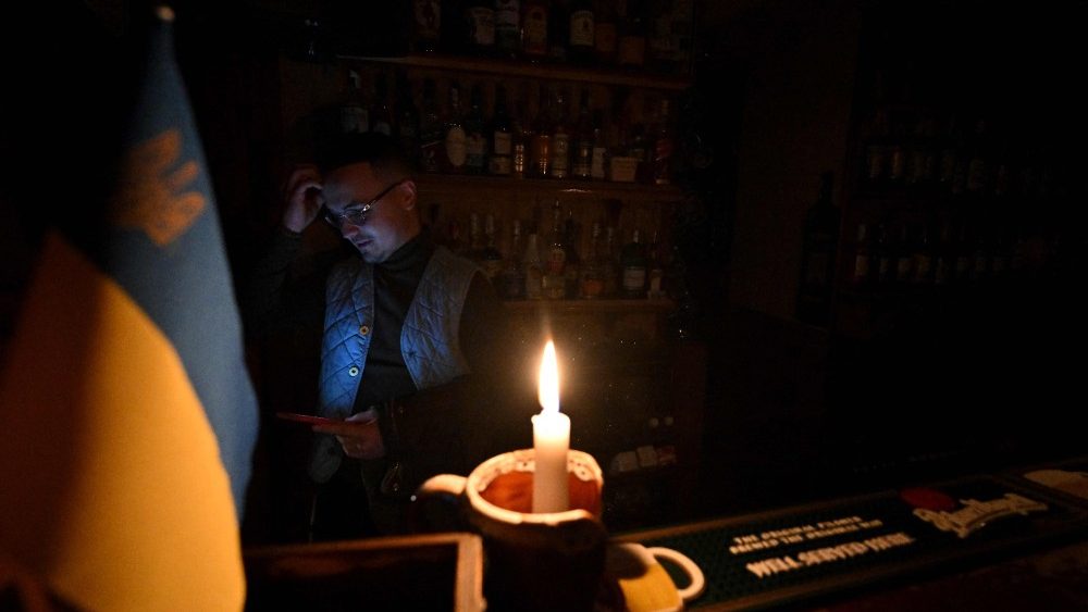 Esta fotografia tirada em 24 de outubro de 2022 mostra um barman reagindo enquanto olha para seu smartphone  luz de velas durante um corte de energia em um bar no centro da capital ucraniana de Kyiv. - Desde 10 de outubro, o sistema eltrico ucraniano foi fortemente afetado por vrios ataques russos que atingiram a infraestrutura de energia. Para evitar um apag?o total, a operadora nacional Ukrenergo implementou cortes de energia programados na capital, bem como em muitas cidades e regi?es da Ucr?nia. (Foto de Sergei SUPINSKY/AFP)