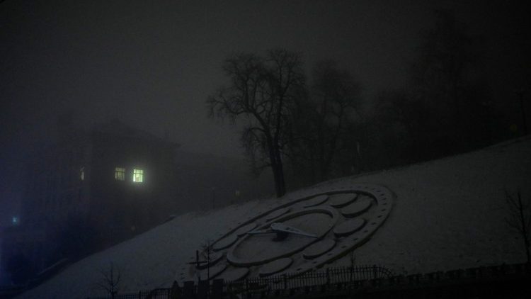 Esta fotografia tirada em 24 de novembro de 2022 mostra o Relógio de Flores coberto de neve e luz saindo de uma janela em uma noite de nevoeiro em Kyiv, em meio à invasão russa da Ucrânia. - A Ucrânia lutou em 25 de novembro de 2022 para fornecer água e energia a milhões de pessoas cortadas depois que a Rússia lançou dezenas de mísseis de cruzeiro que atingiram a já debilitada rede elétrica do país. (Foto de BULENT KILIC/AFP)