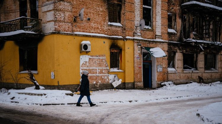 Une femme marche près d'un pan de mur d'un bâtiment endommagé d'où un groupe de personnes a essayé de voler une œuvre du célèbre artiste britannique Banksy dans la ville de Gostomel, près de Kiev, le 3 décembre 2022.