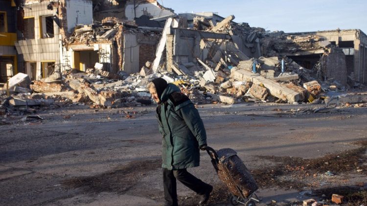 Idosa com sua bagagem passa diante de prédio destruído em Bakhmut, região de Donetsk, em 4 de dezembro de 2022. (Photo by Yevhen Titov)