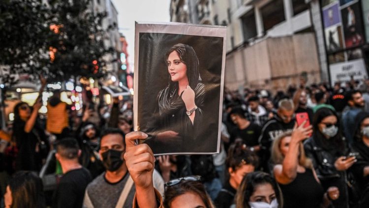 Des manifestants iraniens montrant une photo de Mahsa Amini, une kurde iranienne de 22 ans, décédée en septembre dernier quelques heures après son arrestation par la police des mœurs, pour infraction au code vestimentaire strict de la République islamique.