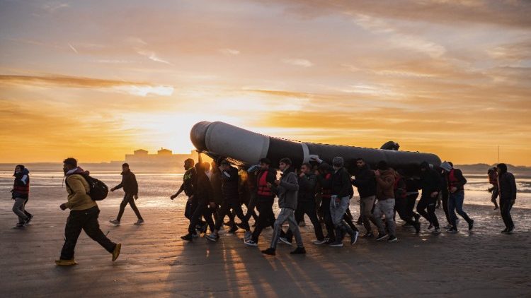 Migranten tragen ein kleines Schlauchboot auf ihren Schultern, um damit über den Ärmelkanal in Richtung Großbritannien überzusetzen