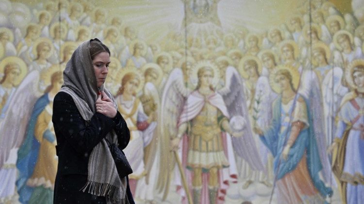 Žena prochází kolem fresek na vnější zdi Kláštera svatého Michala v Kyjevě 25. prosince 2022 během ruské invaze na Ukrajinu. 