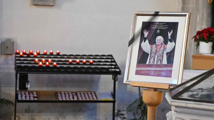Votive candles near picture of Pope Emeritus Benedict XVI
