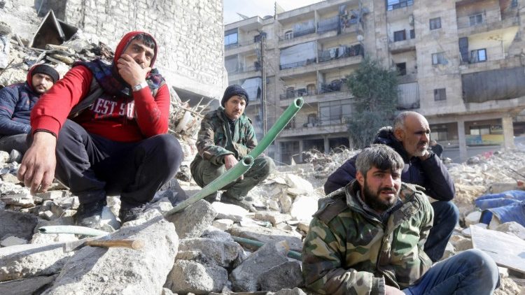  People watch as rescue teams search for victims and survivors under the rubble in Aleppo