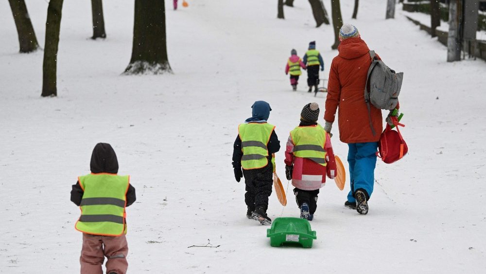 Crian?as pequenas puxam um tren enquanto sobem uma encosta na neve na cidade de Lviv, no oeste da Ucr?nia, em 7 de fevereiro de 2023, em meio  invas?o russa da Ucr?nia. (Foto de YURIY DYACHYSHYN / AFP)
