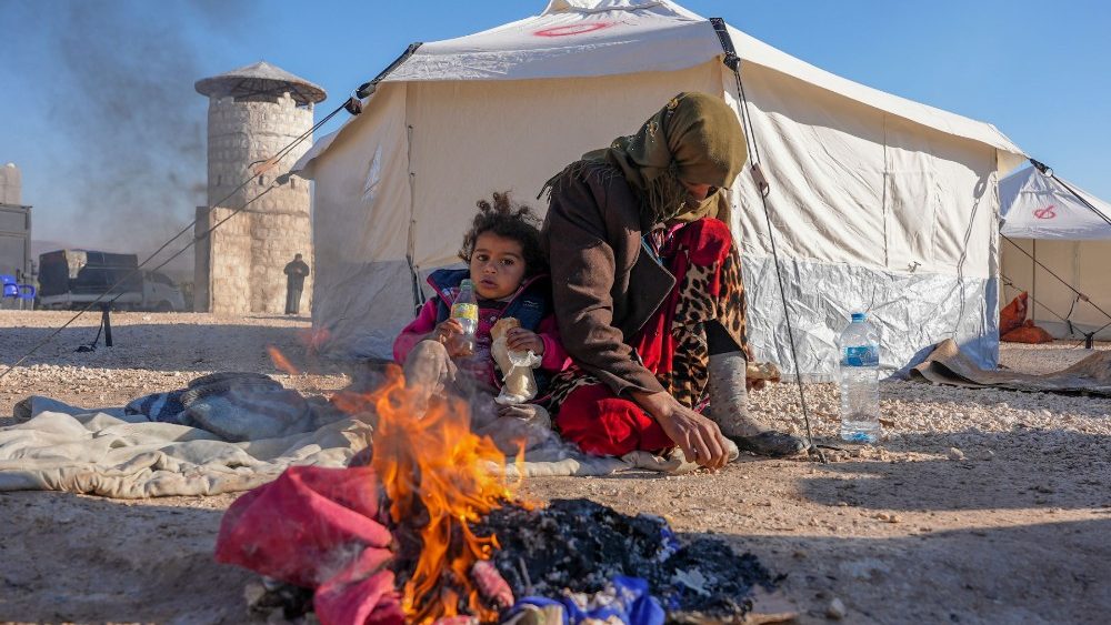 Srios se aquecem em um incndio em um abrigo improvisado para pessoas que ficaram desabrigadas, perto da cidade de Jindayris, controlada pelos rebeldes, em 8 de fevereiro de 2023, dois dias aps um terremoto mortal atingir a Turquia e a . (Foto de Rami al SAYED/AFP)
