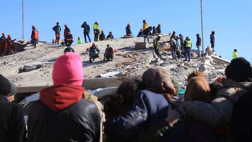 People watch as rescuers and civilians look for survivors under the rubble of collapsed buildings in Nurdagi, in the countryside of Gaziantep, on February 9, 2023, three days after a deadly earthquake that hit Turkey and Syria. (Photo by Zein Al RIFAI / AFP)