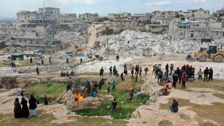 Residents in the Syrian town of Harim watch as search and rescue operations continue