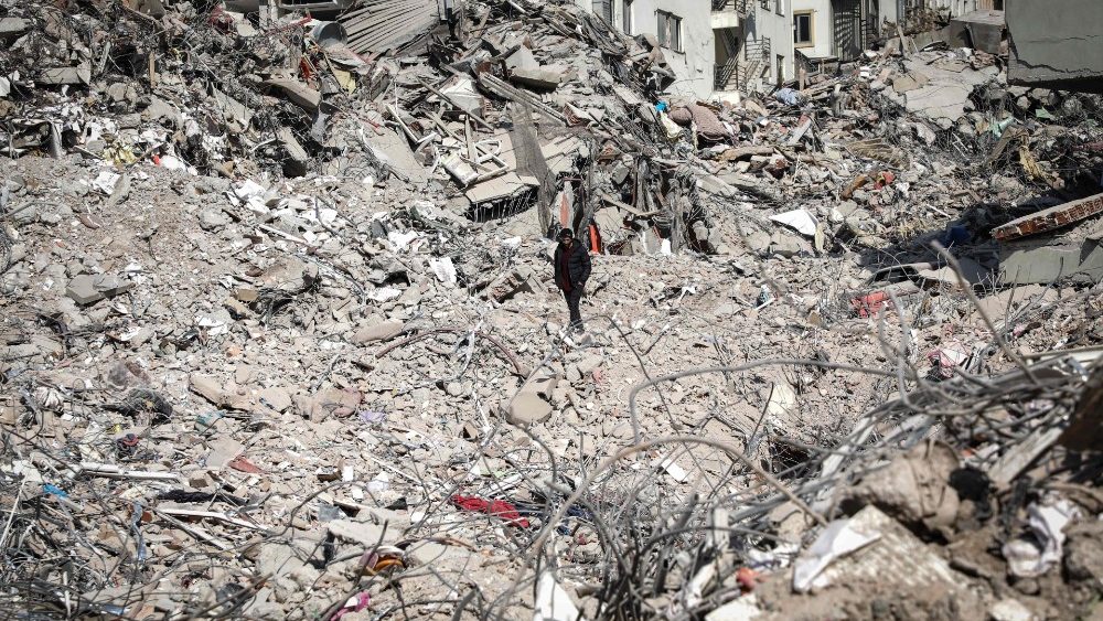 Um homem caminha sobre os escombros de edifcios desabados em Kahramanmaras, sudeste da Turquia, em 18 de fevereiro de 2023. (Photo by Zein Al RIFAI / AFP)