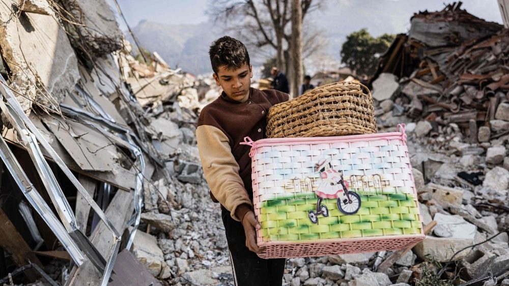 Mustafa Ozdimir ajuda sua famlia enquanto eles coletam mercadorias de sua loja destruda na cidade de Antakya em 19 de fevereiro de 2023. (Foto de Sameer Al-DOUMY / AFP)