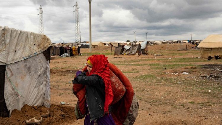 Una mujer transporta sbanas empapadas de agua en el campo de desplazados internos de Sahlat al-Banat, en Raqa, norte de Siria, el 16 de marzo.
