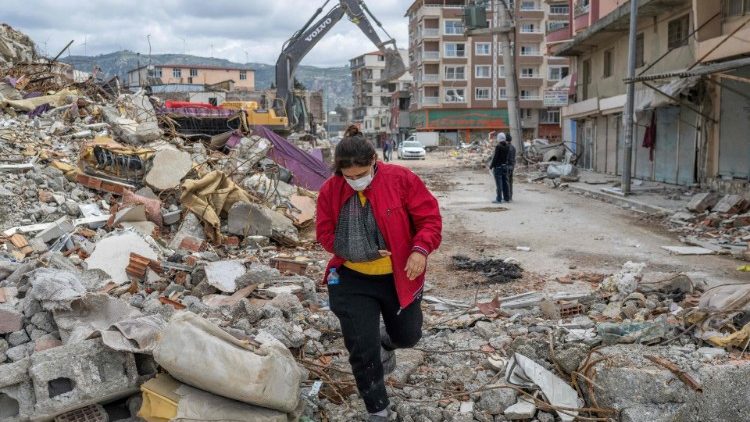 A woman walks on the rubble of a collapsed building in southeast Trkiye