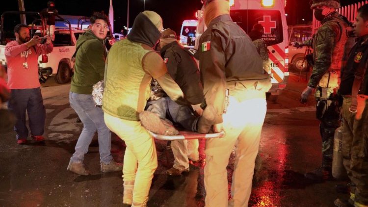 A migrant injured in a fire in an immigration station in Mexico is carried to a waiting ambulance