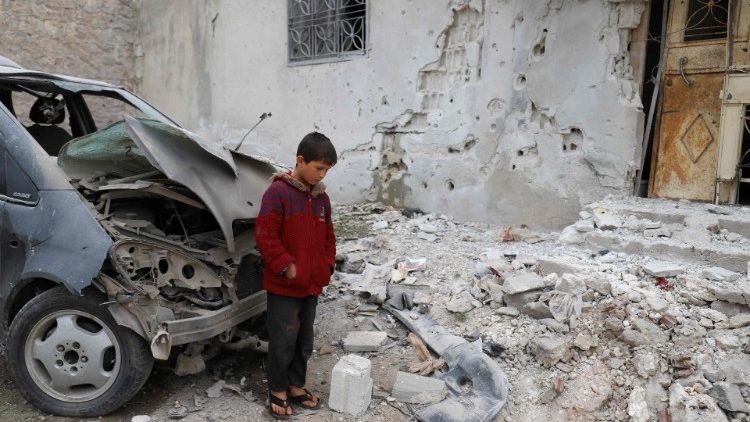 A boy looks at a damaged house following a reported bombing by government forces