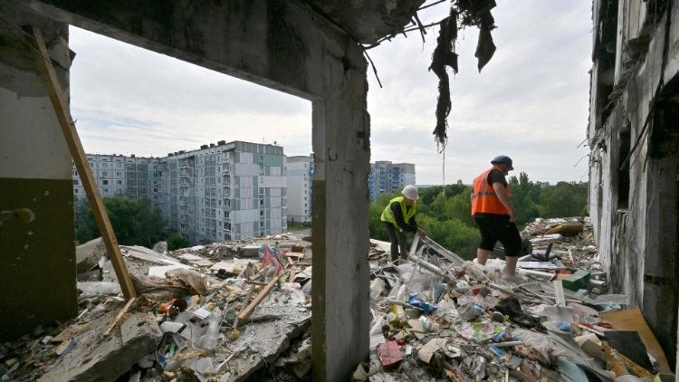 Trabalhadores limpam destroços em um prédio residencial parcialmente destruído após um ataque de míssil russo em 28 de abril de 2023, em Uman, região de Cherkasy, em 26 de maio de 2023. (Foto de Sergei SUPINSKY / AFP)