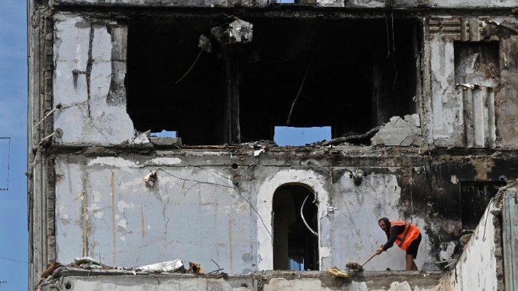 Um trabalhador limpa os escombros em um prédio residencial parcialmente destruído após um ataque de míssil russo em 28 de abril de 2023, em Uman, região de Cherkasy, em 26 de maio de 2023. (Foto de Sergei SUPINSKY / AFP)