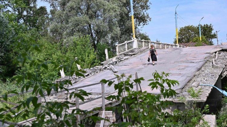 Uma mulher caminha sobre uma ponte destruída sobre o rio Vovcha em Vovchans'k, região de Kharkiv, em 18 de julho de 2023, em meio à invasão russa da Ucrânia. (Foto de SERGEY BOBOK / AFP)
