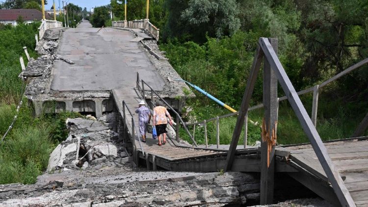 Pessoas caminham em uma ponte destruída sobre o rio Vovcha em Vovchans'k, região de Kharkiv, em 18 de julho de 2023, em meio à invasão russa da Ucrânia. (Foto de SERGEY BOBOK / AFP)
