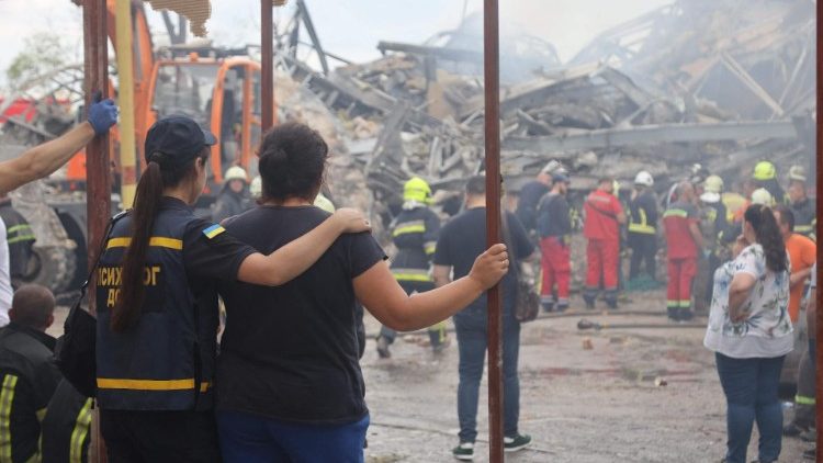 As pessoas assistem enquanto as equipes de resgate ucranianas desmontam os escombros de um prédio administrativo destruído no centro de Odesa após um ataque com mísseis em 20 de julho de 2023, em meio à invasão russa da Ucrânia. (Foto de Oleksandr GIMANOV / AFP)