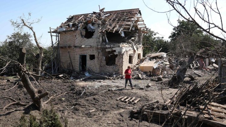 Um residente local passa por uma cratera e uma casa residencial destruída após um ataque com mísseis na região de Kiev, em 27 de agosto de 2023, em meio à invasão russa da Ucrânia. (Foto de Anatolii STEPANOV/AFP)