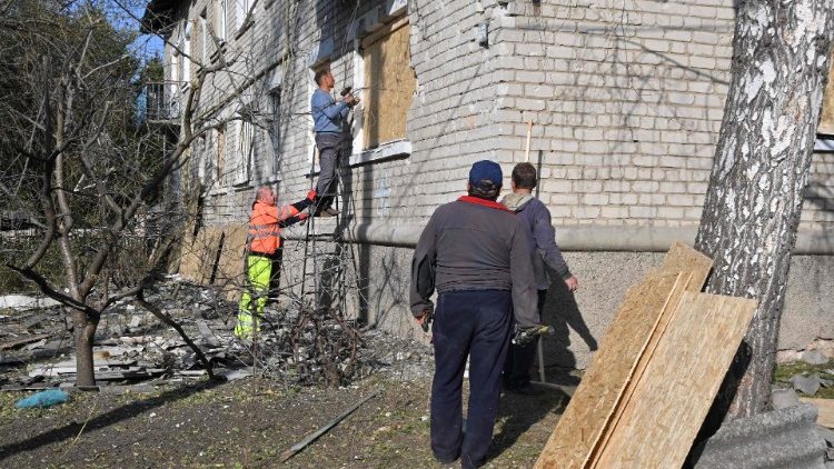 Um homem coloca uma tábua de madeira para proteger uma janela de um edifício que foi danificado após o recente bombardeio russo em um assentamento urbano de Borova, região de Kharkiv, em 4 de outubro de 2023, em meio à invasão russa da Ucrânia. (Foto de SERGEY BOBOK/AFP)