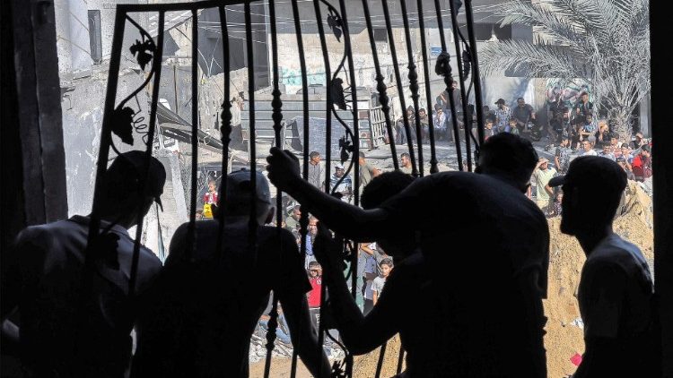 Men remove a metal grate from a building bombarded in Rafah