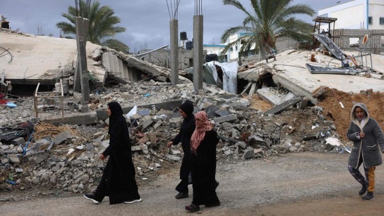 Palestinians walk past destroyed houses in Khuzaa, near Khan Yunis