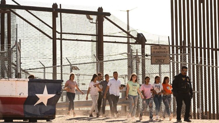 Migrants board vans after waiting along the US border wall