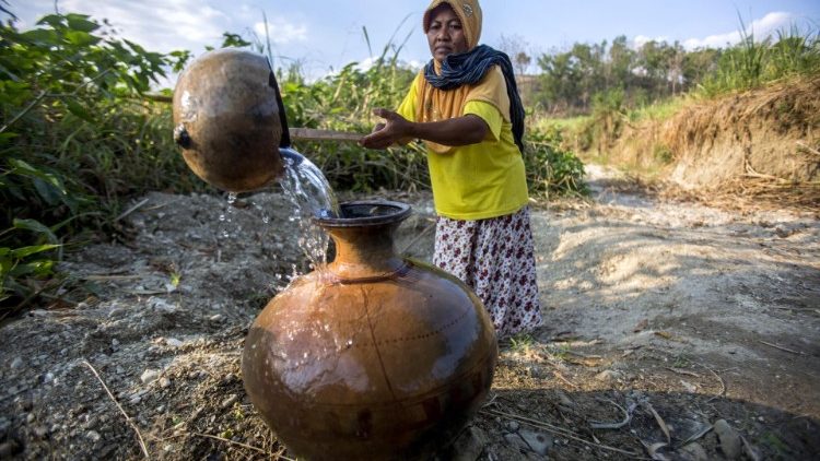 A villager collects water from a well during a drought in Indonesia